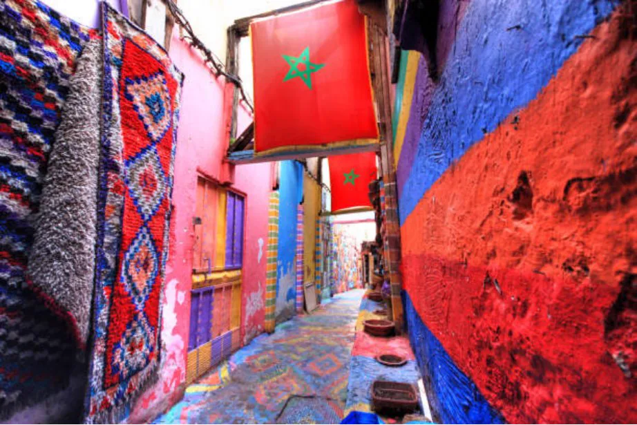 Colourful Moroccan medina lane with flags and woven textiles